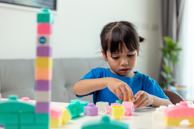 Entzückendes kleines Mädchen, das Spielzeugblöcke in einem hellen Raum spielt