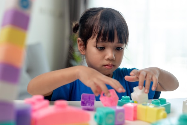 Entzückendes kleines Mädchen, das Spielzeugblöcke in einem hellen Raum spielt