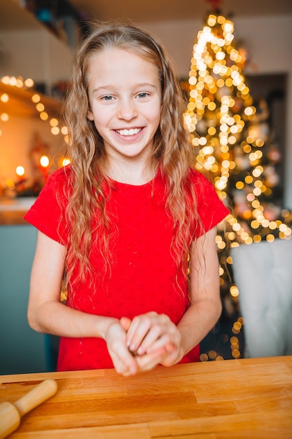 Entzückendes kleines mädchen, das weihnachtslebkuchenplätzchen backt