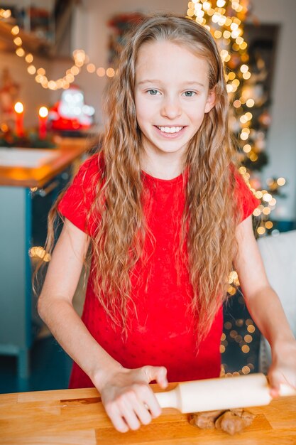 Entzückendes kleines Mädchen, das Weihnachtslebkuchenplätzchen backt