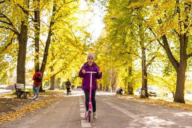 Entzückendes kleines Mädchen hat Spaß auf dem Roller im Freien