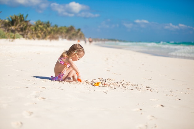 Entzückendes kleines Mädchen im Badeanzug, der am tropischen karibischen Strand spielt