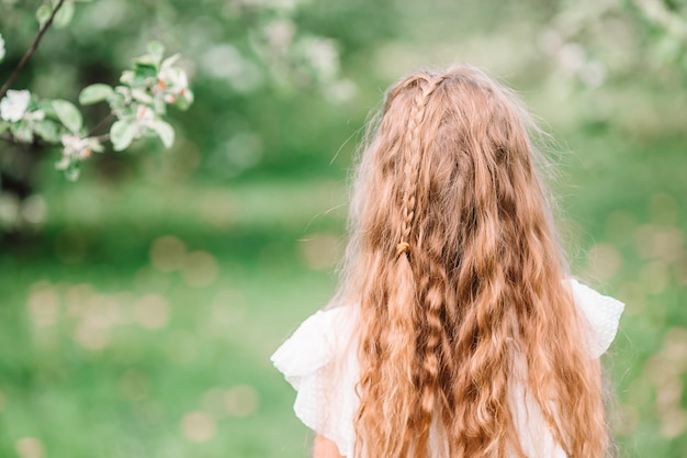 Entzückendes kleines Mädchen im blühenden Apfelgarten am schönen Frühlingstag