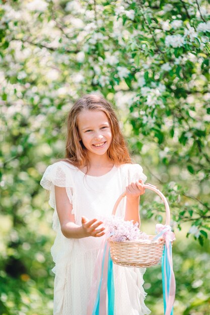 Entzückendes kleines Mädchen im blühenden Apfelgarten am schönen Frühlingstag