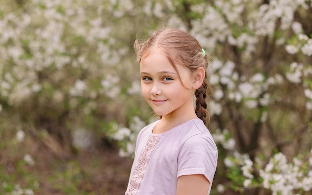 Entzückendes kleines Mädchen im blühenden Kirschgarten am schönen Frühlingstag