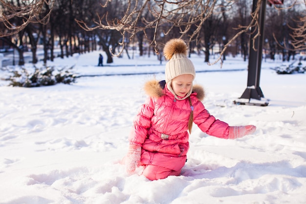 Entzückendes kleines Mädchen im Freien im Park an einem Wintertag