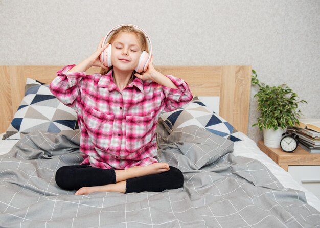 Entzückendes kleines Mädchen in den Kopfhörern genießt mit einer Musik.