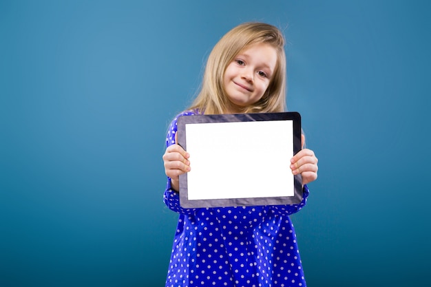 Entzückendes kleines Mädchen in der leeren Tablette des purpurroten Kleidergriffs