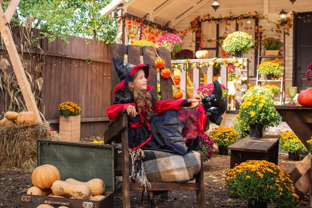 Entzückendes kleines Mädchen mit Halloween-Kostüm, das Spaß auf einem Kürbisbeet an einem schönen Herbsttag hat