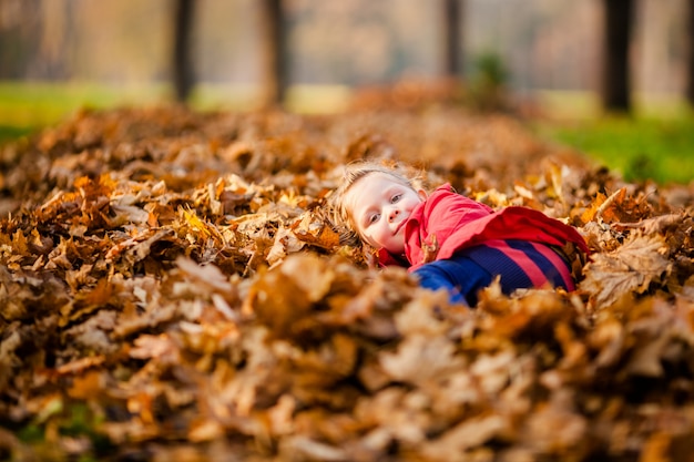 Entzückendes kleines Mädchen mit Herbstblättern