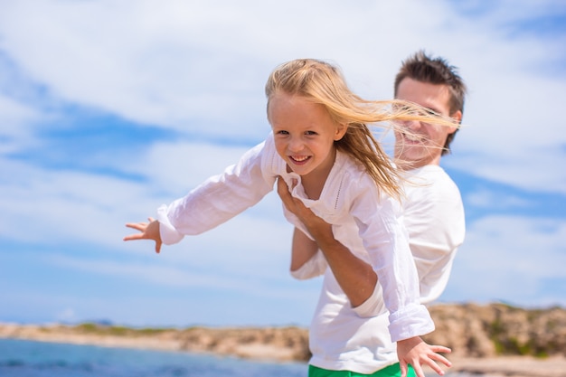 Entzückendes kleines Mädchen und glücklicher Vater während der Strandferien