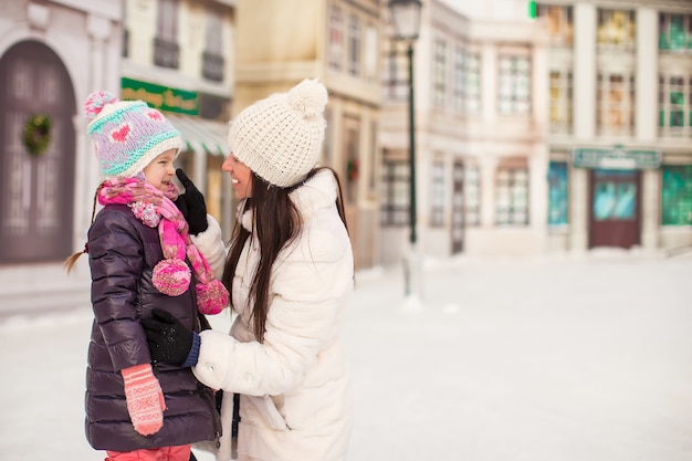 Entzückendes kleines Mädchen und ihre junge Mutter auf einer Eisbahn