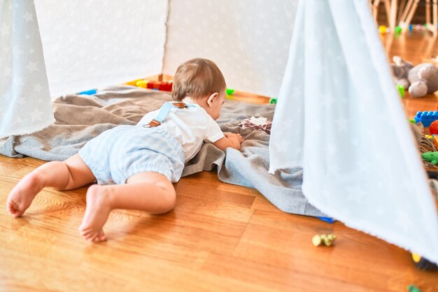 Foto entzückendes kleinkind, das im kindergarten mit vielen spielsachen herumspielt