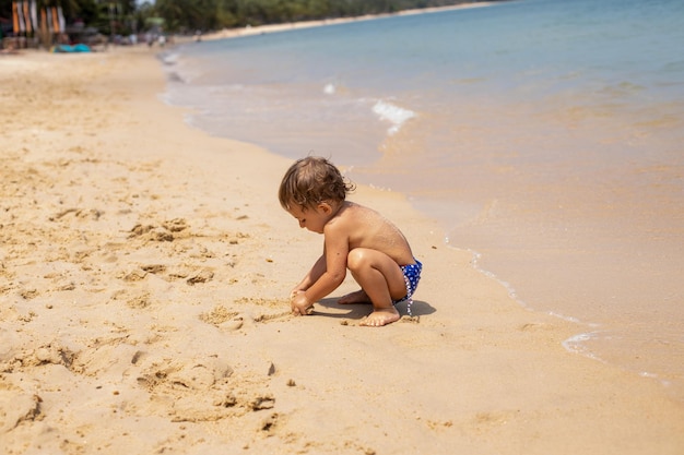 Entzückendes Kleinkind Kleinkind hat Spaß beim Spielen am Sandstrand des tropischen Meeres