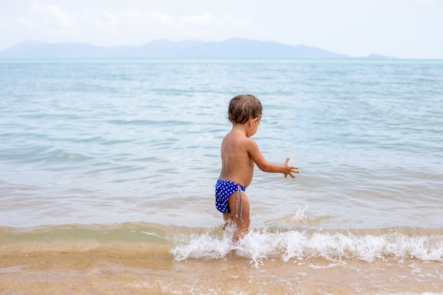 Entzückendes Kleinkind Kleinkind hat Spaß beim Spielen am Sandstrand des tropischen Meeres
