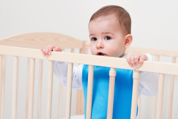 Entzückendes Kleinkindbaby, das auf dem weißen Bett sitzt