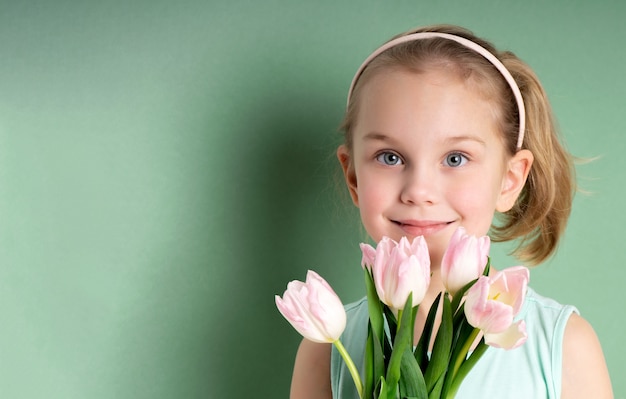 Entzückendes lächelndes kleines Mädchen mit Tulpen über Grün