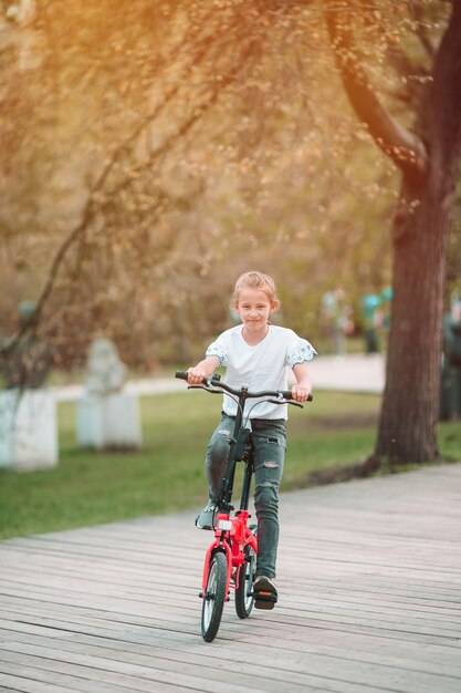 Entzückendes Mädchen, das ein Fahrrad am schönen Sommertag im Freien reitet