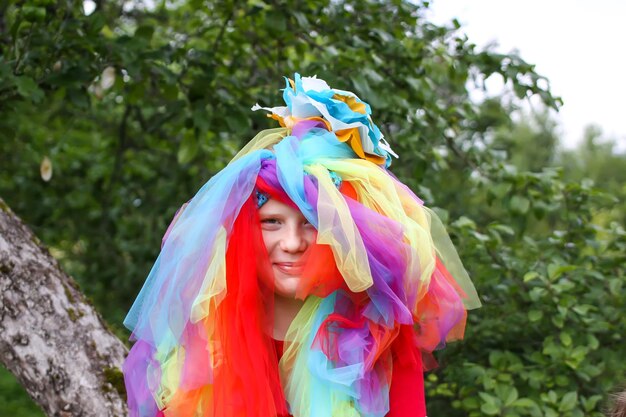 Entzückendes Mädchen im bunten Regenbogenkleid auf dem Kopf, das draußen spielt