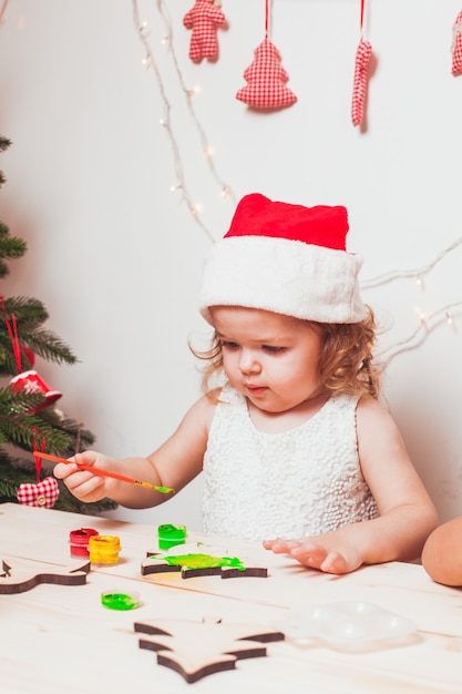 Entzückendes Mädchen malt hölzerne Weihnachtsfiguren