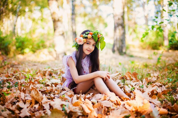 Entzückendes Mädchen mit gelben Blättern sitzt