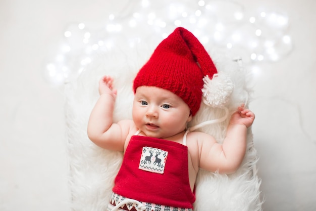 Entzückendes schlafendes neugeborenes Baby, das Weihnachtsmann-Hut Weihnachten Neujahr trägt