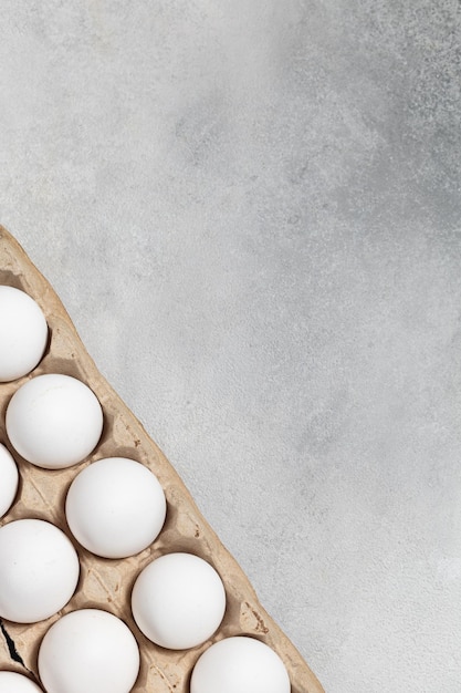 Envasado de huevos de gallina blanca sobre un fondo gris