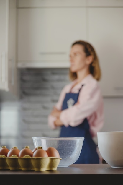 Envasado de huevos y tazones para hacer masa en el fondo de la cocina y la mujer que cocina en casa