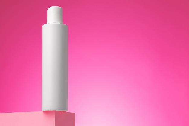 Envase cosmético blanco en blanco sobre fondo rosa