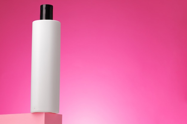 Envase cosmético blanco en blanco sobre fondo rosa