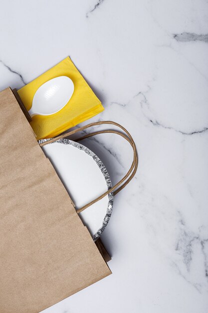 Envases de aluminio para comida para llevar preparados para su entrega en bolsas de papel reciclable. Endecha plana