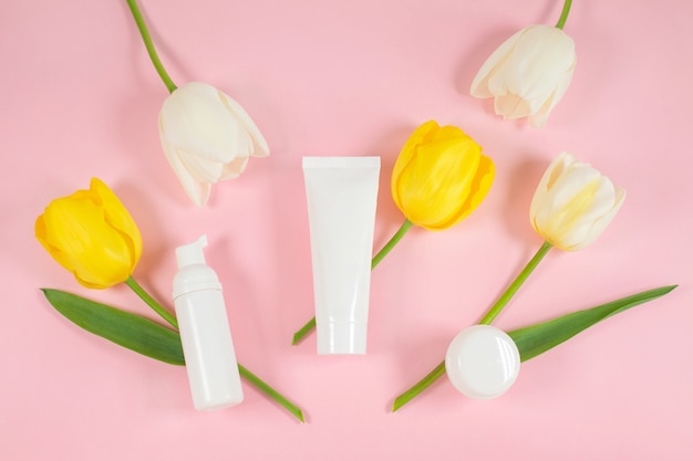 Envases de botellas de cosméticos blancos en flores de tulipanes amarillos y blancos