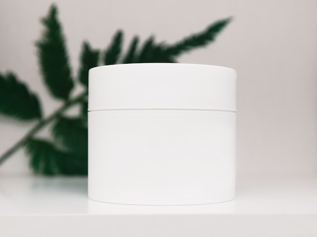 Envases de botellas de cosméticos con hojas de hierbas verdes, etiqueta en blanco para la marca, producto de belleza natural.