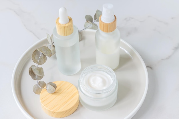 Envases de cosméticos Conjunto de diferentes botellas cosméticas de crema o suero en una bandeja de cerámica Envases en blanco Concepto de producto de spa de belleza natural BeautyMockup