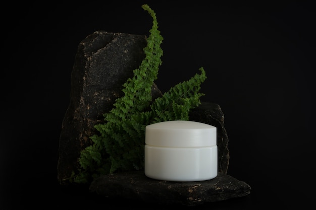 Envases de crema cosmética natural sin marca de pie en el podio de piedra. Presentación crema sobre fondo negro. Bosquejo. Concepto de tendencia en materiales naturales. Cosmética natural, cuidado de la piel.