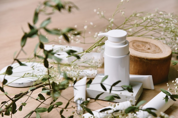 Envases de envases de botellas de cosméticos con hojas de hierbas verdes, etiqueta en blanco para la marca orgánica, concepto de producto de belleza natural para el cuidado de la piel.