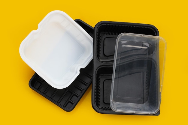 Envases de plástico para alimentos sobre fondo amarillo.