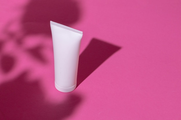 Envases de productos para el cuidado de la piel en mesa rosa brillante