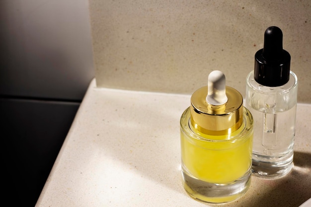 Envases de vidrio con productos cosméticos para el cuidado de la piel en la parte superior del mueble del baño.