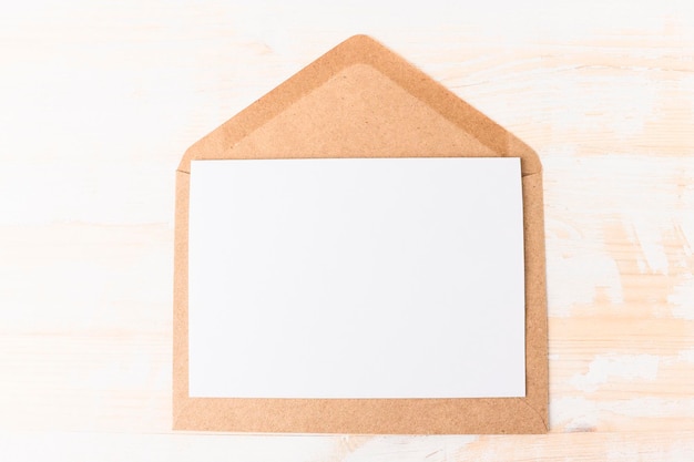 Envelope aberto com uma folha de papel branca com espaço para cópia em uma mesa de madeira