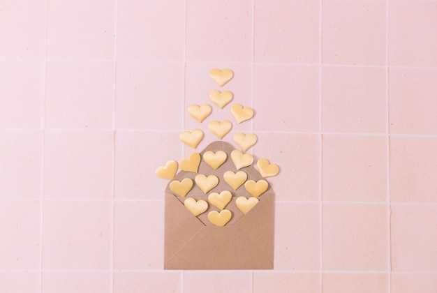 Envelope artesanal com corações caindo em um fundo de azulejos