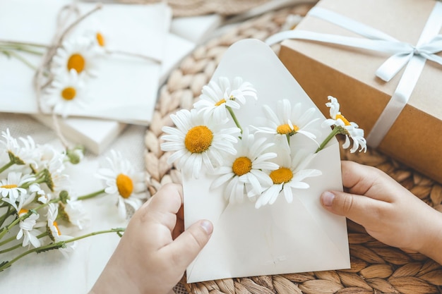 Envelope com margaridas na mão e conceito de férias de decoração estética