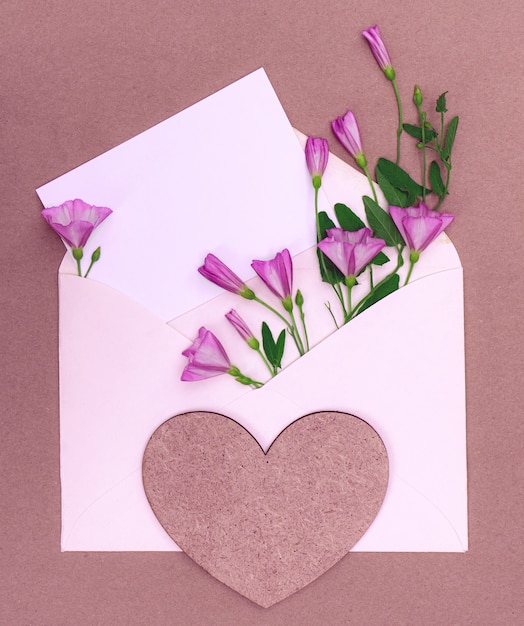 Envelope com um buquê de flores silvestres com um coração e espaço de cópia para o projeto.