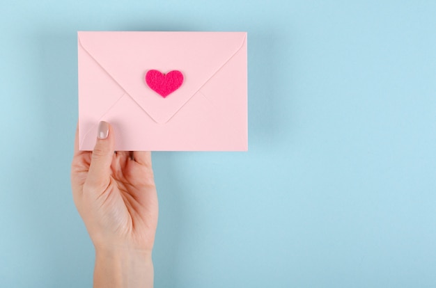 Envelope de papel com composição de coração vermelho sobre fundo azul.