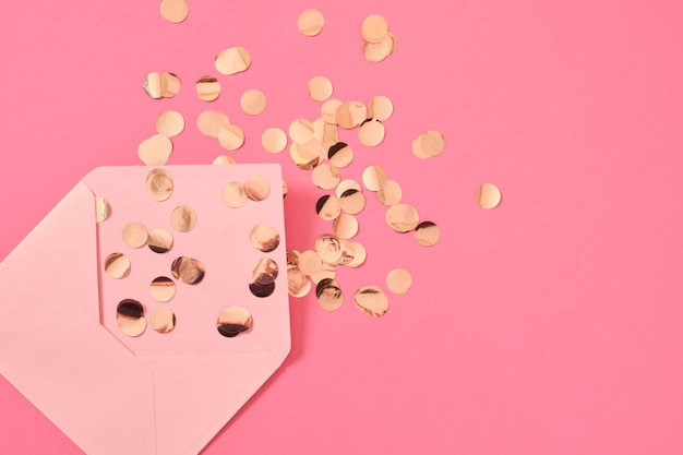 Envelope em branco de papel rosa de confete dourado em um conceito de felicitações de fundo rosa