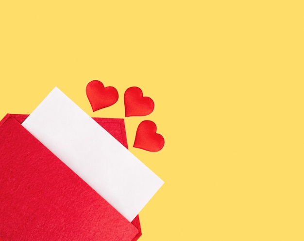 Envelope vermelho aberto com uma folha de papel com um coração em um fundo amarelo. Conceito de feriados do dia dos namorados