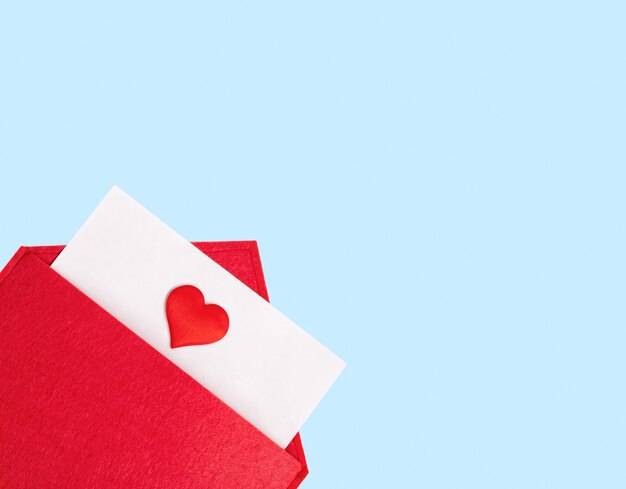 Foto envelope vermelho aberto com uma folha de papel com um coração em um fundo azul