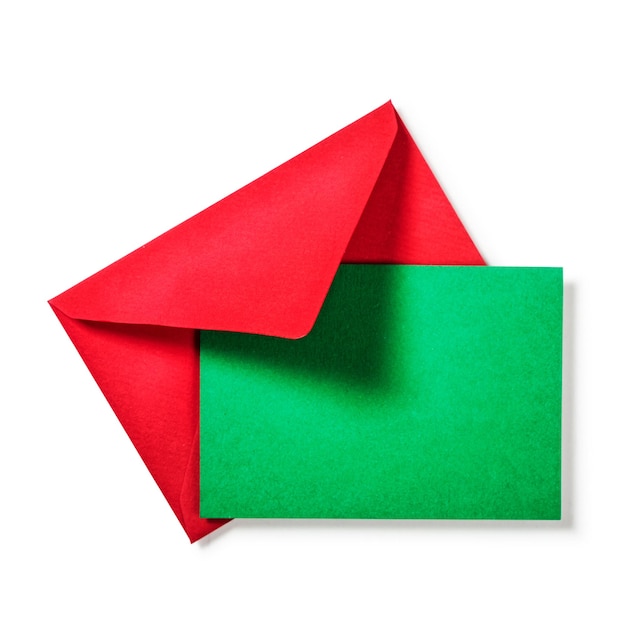 Envelope vermelho com cartão verde no traçado de recorte de fundo branco incluído. copie o espaço. vista superior, configuração plana. temas de natal