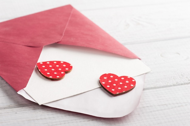 Envelope vermelho com papel vazio e corações vermelhos