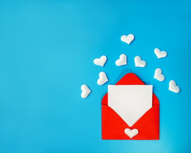 Envelope vermelho com uma carta de amor. Corações sobre um fundo azul. O conceito de coração.